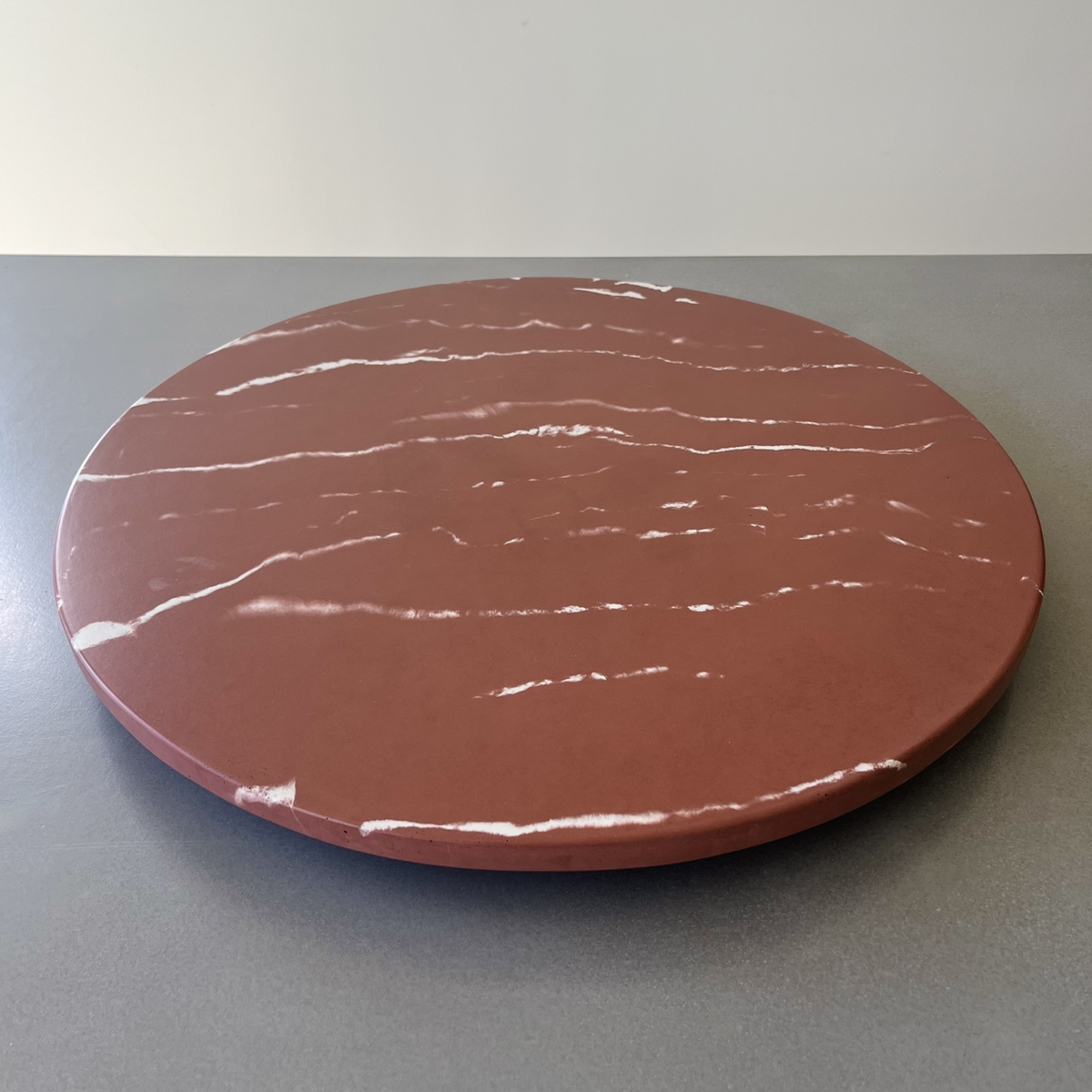 A round bush plum colored marble concrete with white marble-like veining lazy susan. 