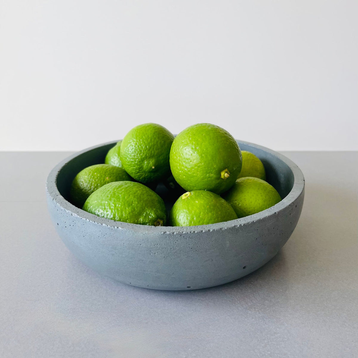 Moon Shadow Solid Concrete Finish Cove Bowl, styled as a fruit bowl. 