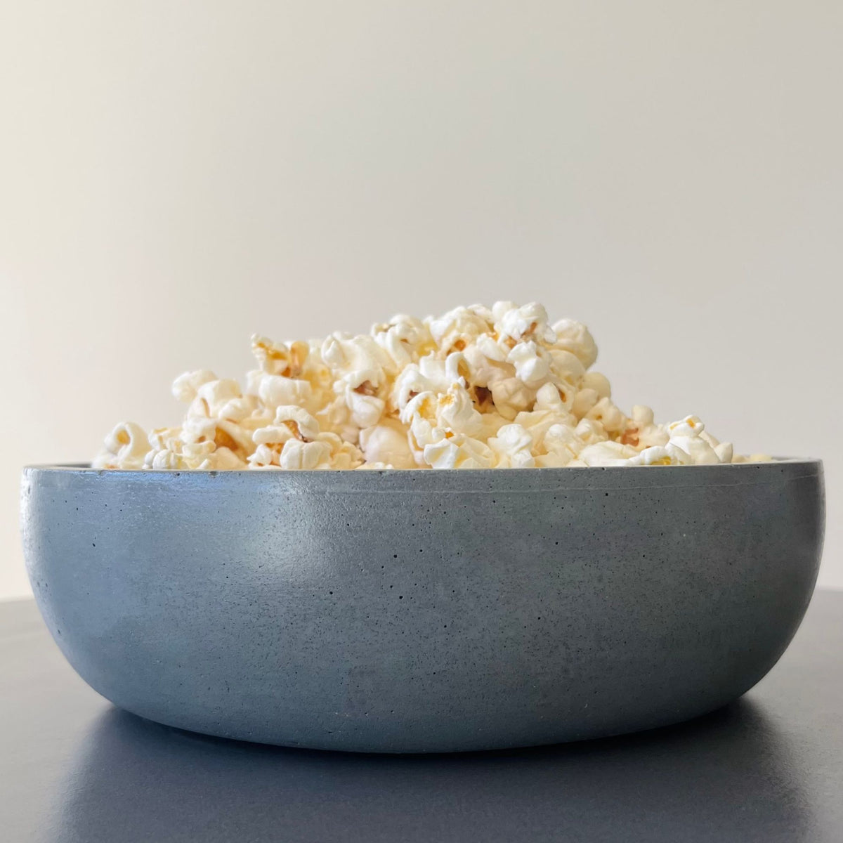 Cove Bowl in the solid concrete Moon Shadow finish. Styled with popcorn
