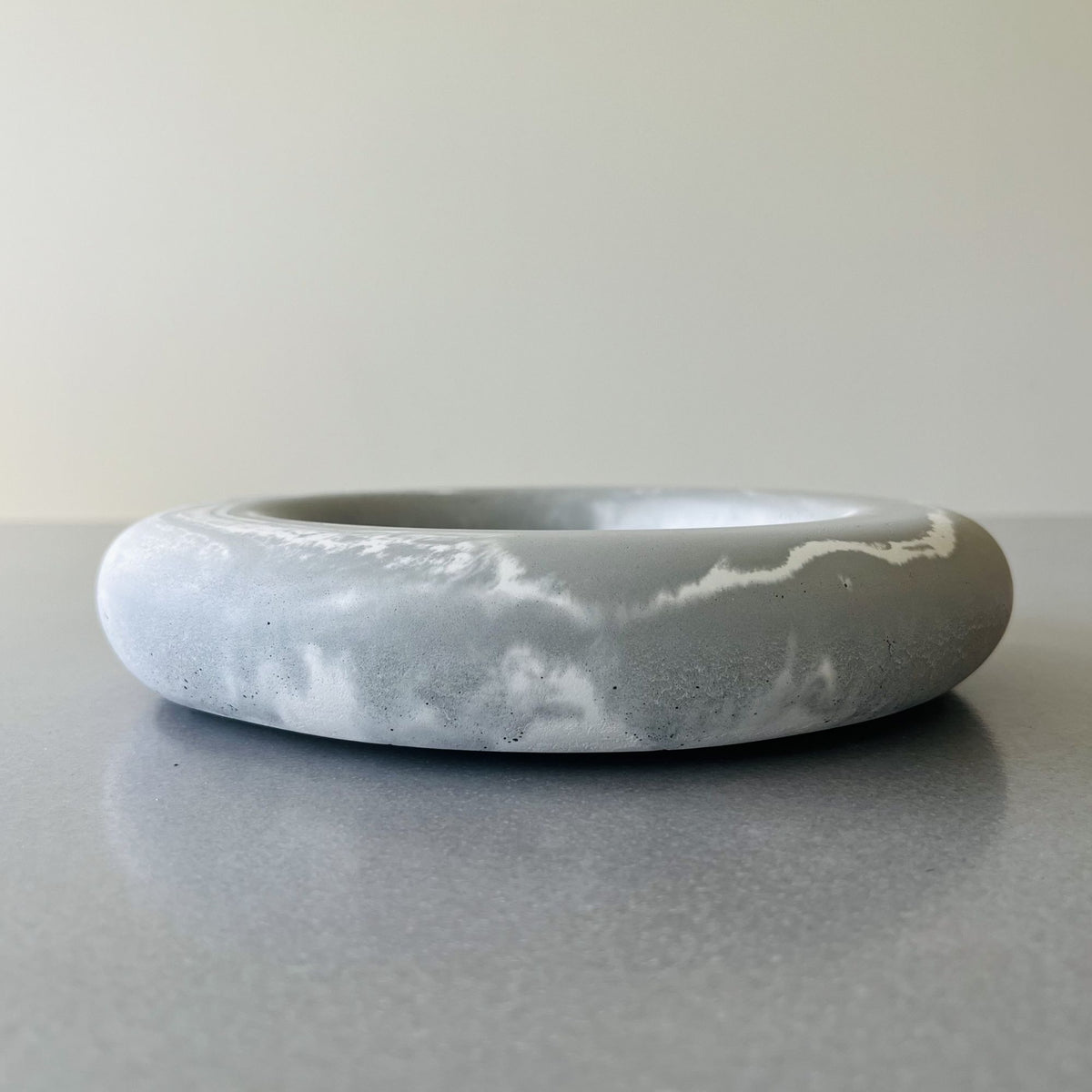 A round concrete decorative bowl is Sea Drift with Marble Concrete Finish